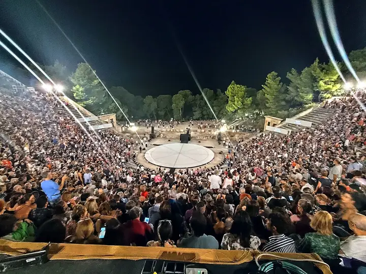 The Ancient Theatre of Epidaurus at night, the audience around the orchestra.